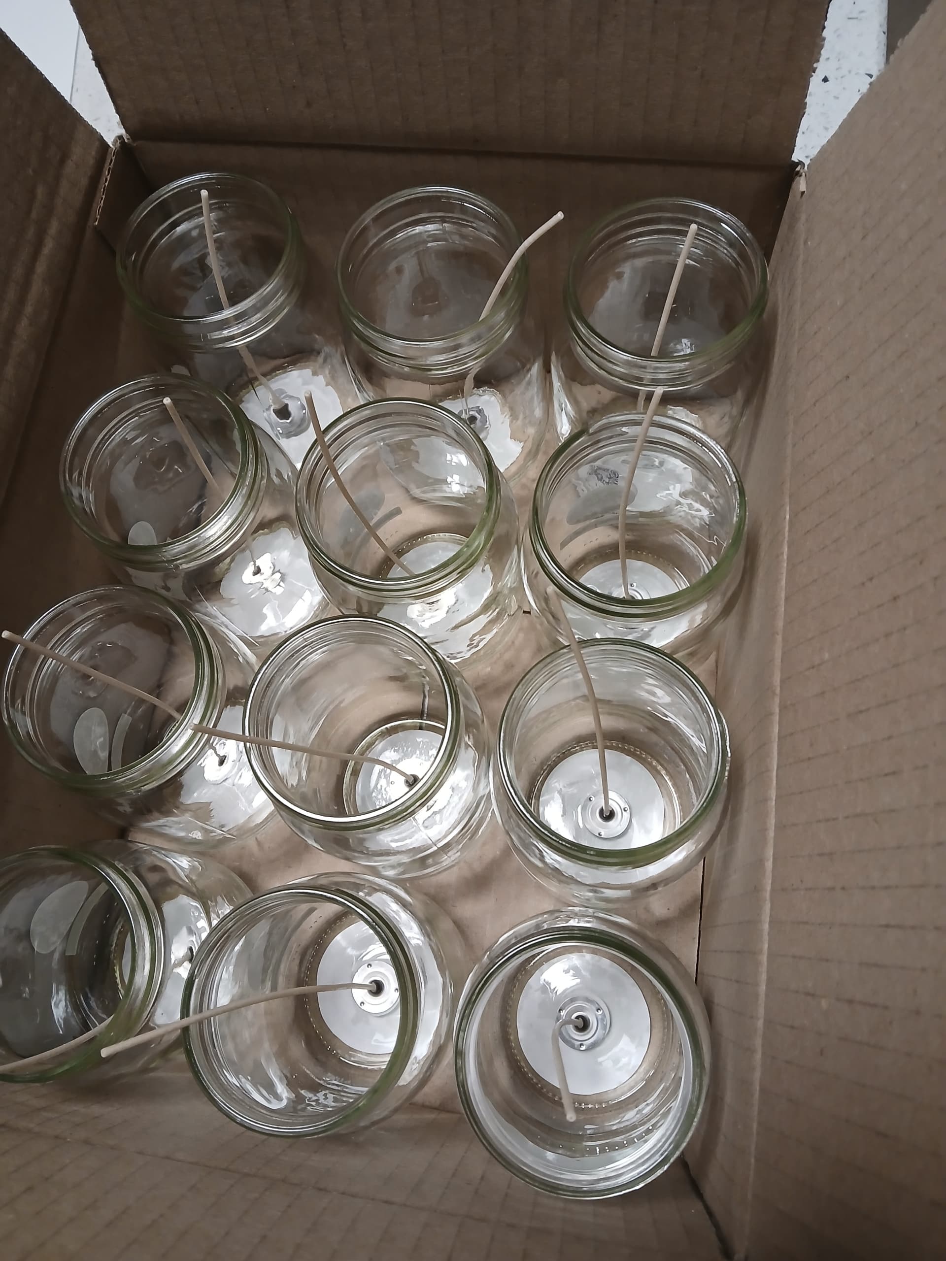 Box of empty glass mason jars with wicks centered, ready for pouring